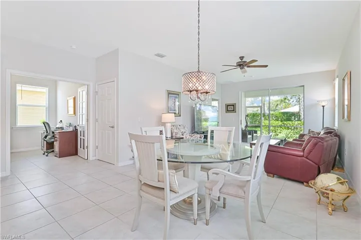 Dining area with light tile patterned flooring, a chandelier, a desk, and a ceiling fan