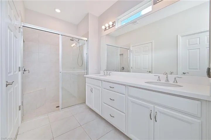 Full bathroom with double vanity, a stall shower, and tile patterned floors