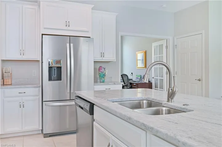 Kitchen with stainless steel appliances, white cabinetry, light stone counters, and light tile patterned flooring