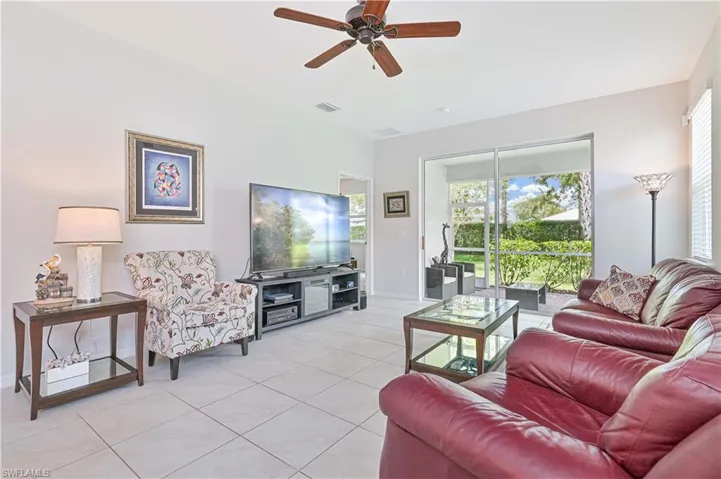 Living room with light tile patterned floors, ceiling fan, and healthy amount of natural light