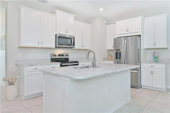 Kitchen featuring appliances with stainless steel finishes, light tile patterned floors, white cabinets, and recessed lighting