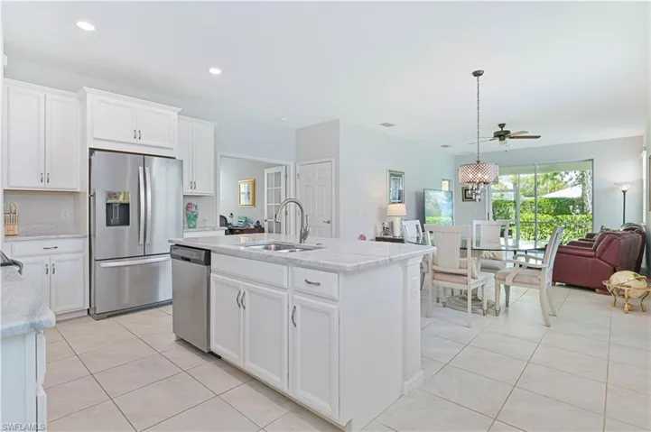 Kitchen featuring appliances with stainless steel finishes, light tile patterned floors, open floor plan, light stone countertops, and white cabinetry