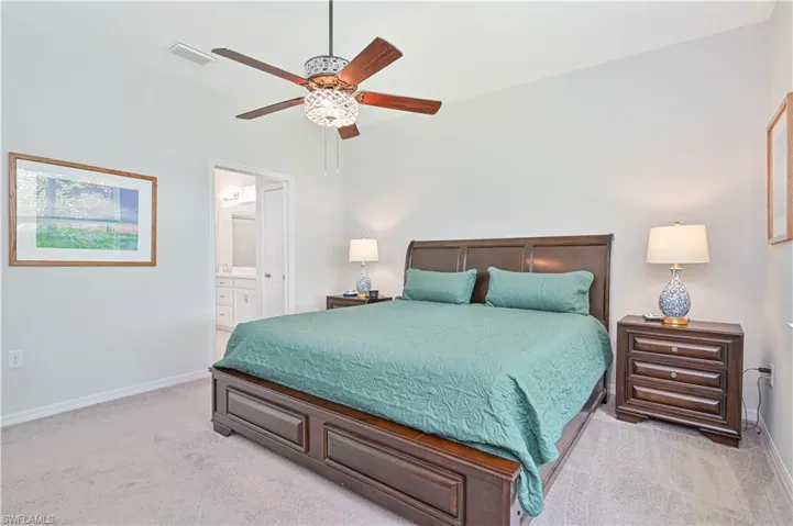 Bedroom with light carpet, ensuite bathroom, and a ceiling fan
