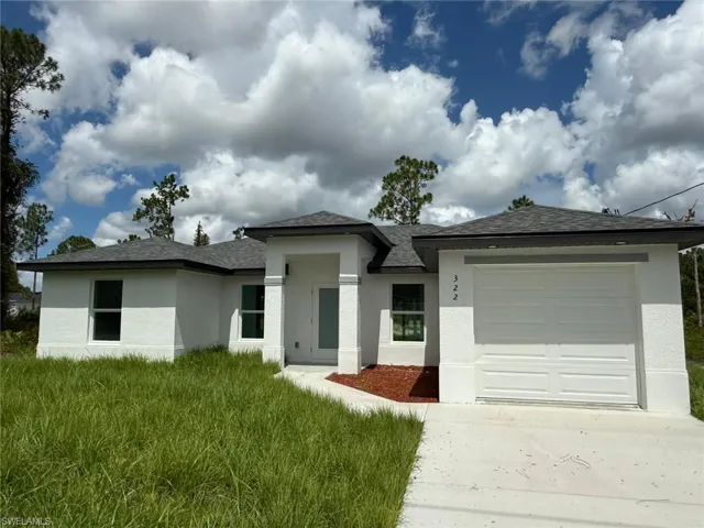 Prairie-style home featuring an attached garage, stucco siding, driveway, and roof with shingles