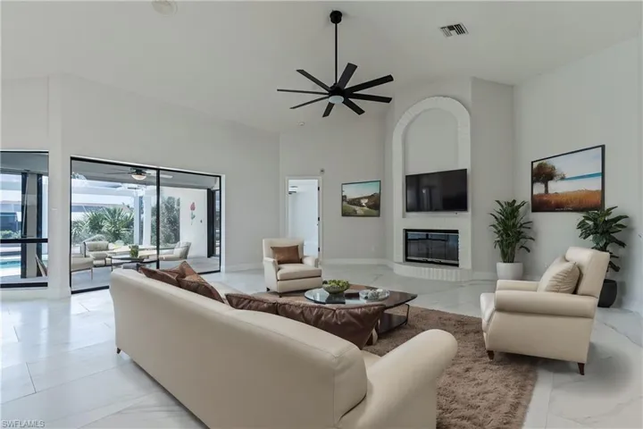 VIRTUALLY STAGED- Tiled living room featuring high vaulted ceiling, a large fireplace, and ceiling fan