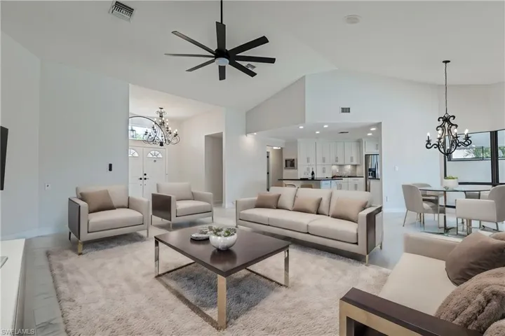 VIRTUALLY STAGED -Living room featuring high vaulted ceiling and ceiling fan with notable chandelier