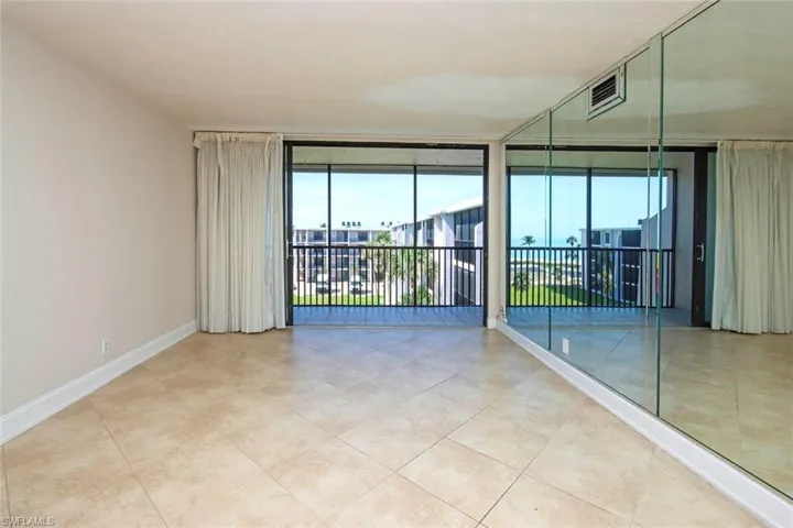 Tiled empty room featuring healthy amount of natural light, a wall of windows, and baseboards