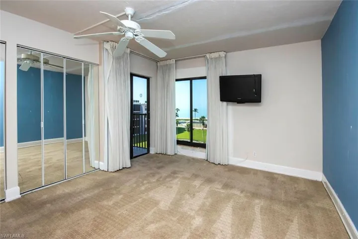 Unfurnished bedroom featuring carpet floors, access to exterior, baseboards, and a ceiling fan