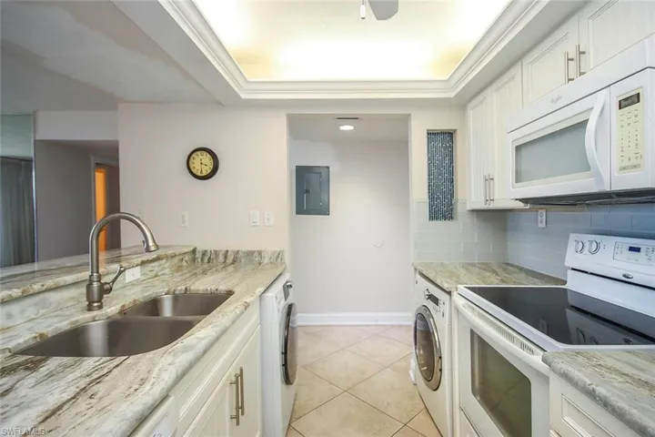 Kitchen with white appliances, a sink, washer / dryer.