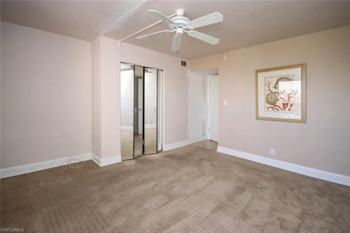 Carpeted guest bedroom featuring ceiling fan and baseboards