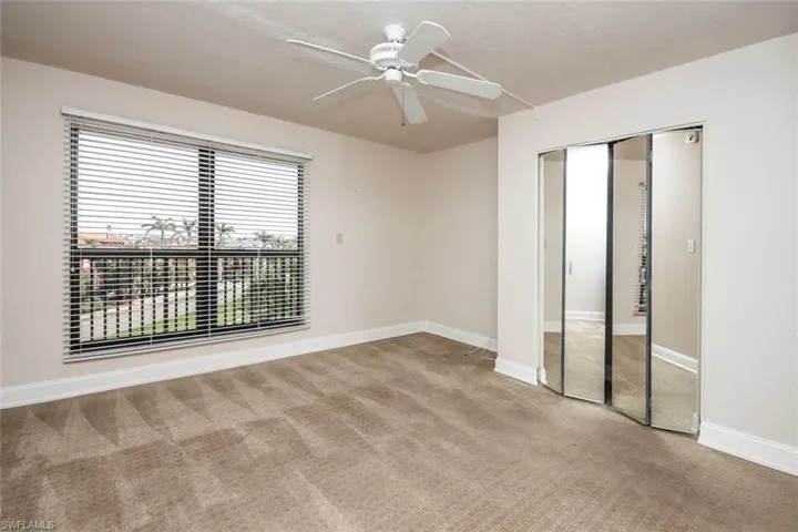 Unfurnished guest bedroom with carpet, baseboards, a ceiling fan, and a closet