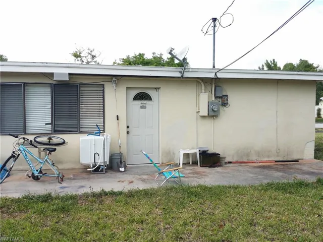 Rear view of house with a patio area, a lawn, and stucco siding