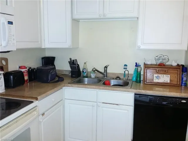 Kitchen with white appliances, white cabinets, and light countertops