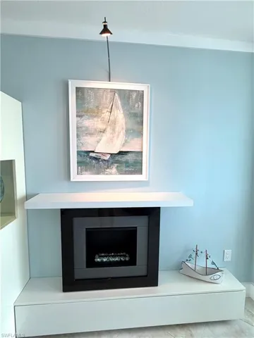 Built-in electric ambient fireplace with a white floating mantel, integrated wall lighting, and white cabinetry