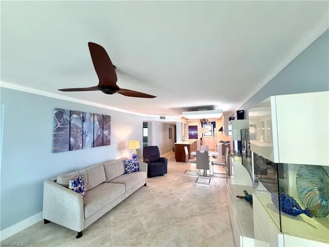 Open-concept living area showcasing tile flooring, soft blue accent walls, and modern ceiling fan