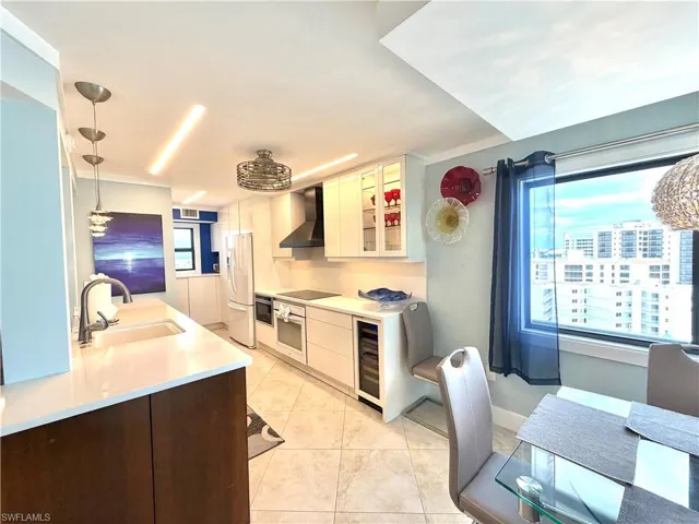 Kitchen featuring white perimeter cabinetry, a built-in wine cooler, upgraded appliances, and a counter-depth refrigerator