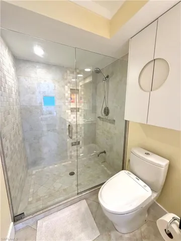 Glass-enclosed shower with a tiled floor and walls, toto bidet