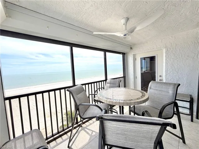 Screened balcony featuring a ceiling fan, tiled flooring, and a glass-paneled door