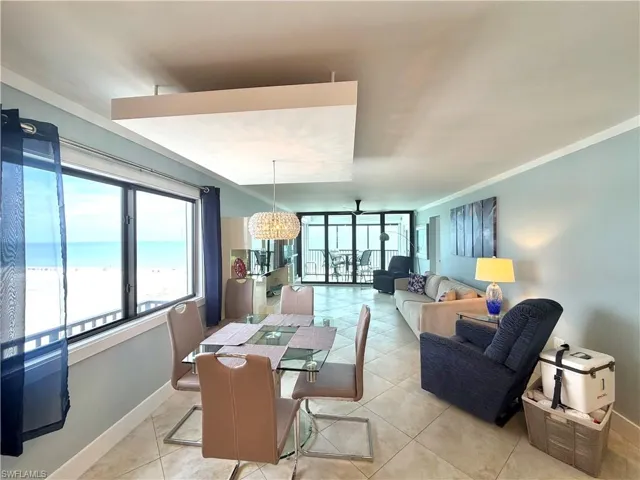 Open-concept living area with large windows, glass sliding doors, tile flooring, and a decorative ceiling fixture