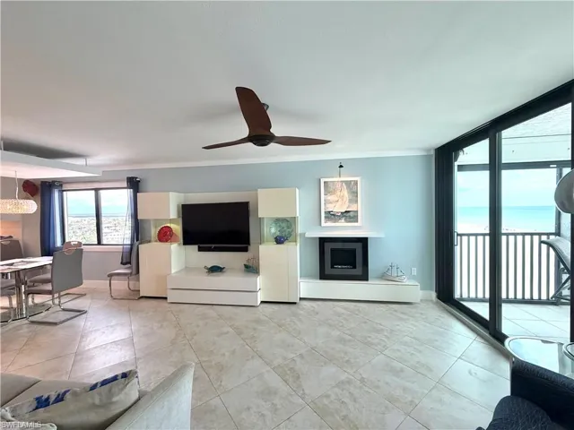 Spacious open-concept living area featuring light-filled interiors with expansive glass sliding doors opening to oceanfront balcony access