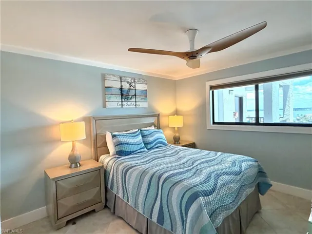 Expansive window with water scenery, crown molding, ceiling fan, and tile flooring