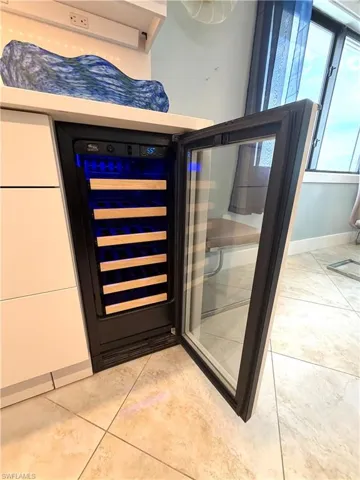 Built-in beverage refrigerator with clear glass door, wood-finish shelving, and integrated lighting