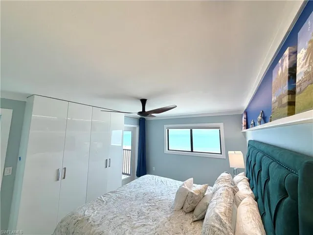 Integrated white cabinetry with sleek handles, overhead ceiling fan, and a window offering natural light and power blind.