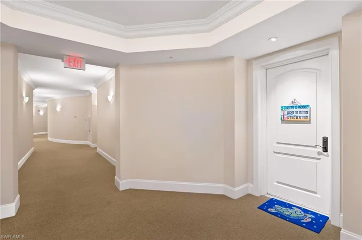 Carpeted foyer featuring baseboards, ornamental molding, and a tray ceiling