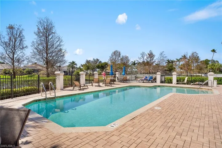 Community pool with a patio area and fence