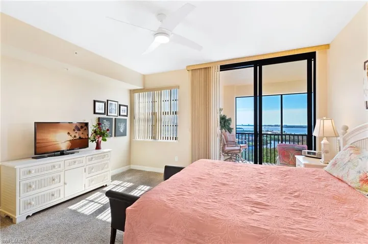 Carpeted bedroom with ceiling fan, access to outside, a water view, and baseboards