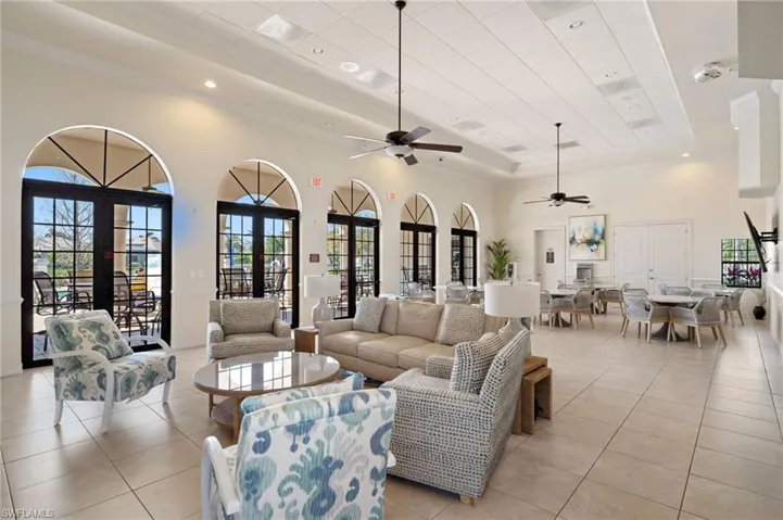 Living room with light tile patterned floors, french doors, a raised ceiling, and a high ceiling