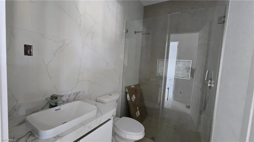 Bathroom with a stall shower, vanity, and tile walls