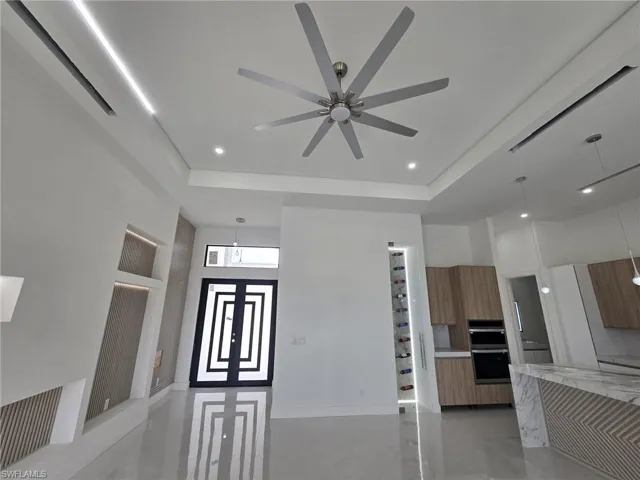 Kitchen with modern cabinets, decorative light fixtures, light stone counters, wood finish cabinetry, and finished concrete floors