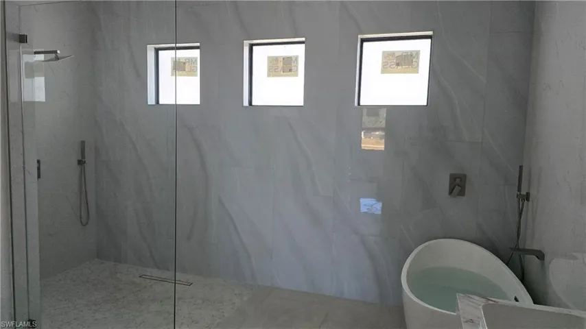 Bathroom featuring a marble finish shower and a freestanding tub