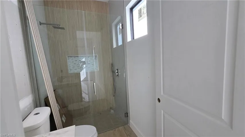 Full bathroom featuring toilet and a shower stall