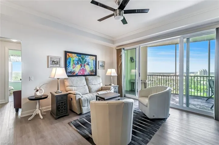 Living area with plenty of natural light, wood finished floors, crown molding, and a ceiling fan