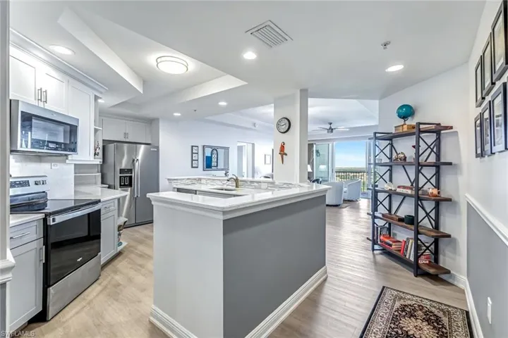 Kitchen featuring appliances with stainless steel finishes, a raised ceiling, light wood-style floors, and recessed lighting