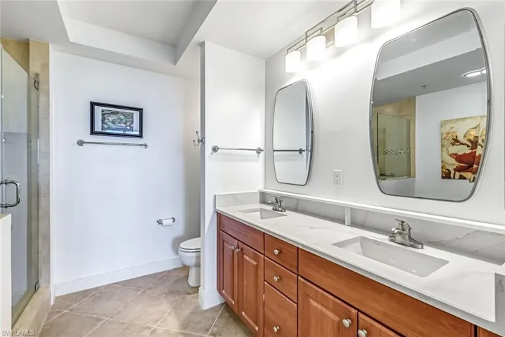 Full bath featuring double vanity, a stall shower, and light tile patterned floors