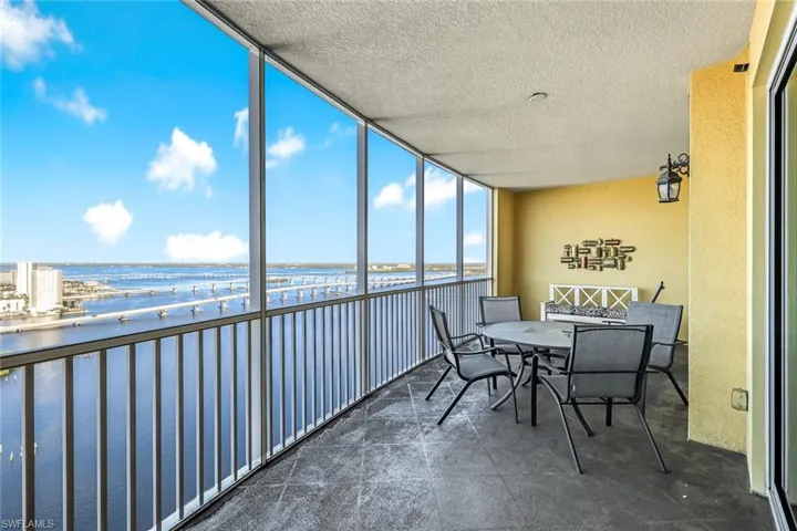 Sunroom featuring a water view, floor to ceiling windows, a textured ceiling, and a textured wall