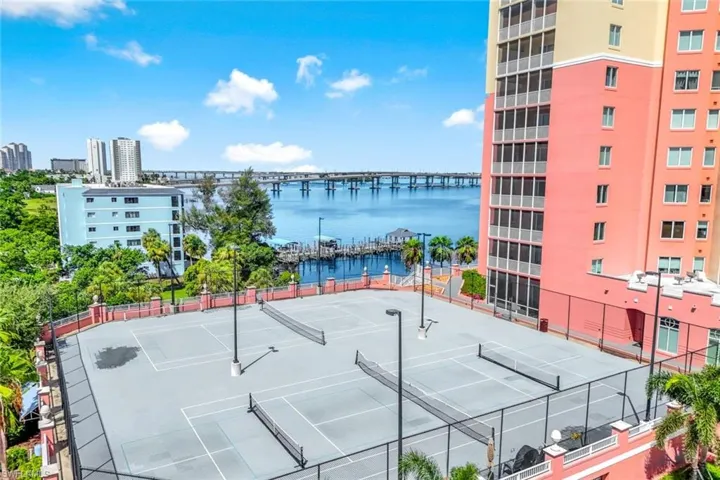 View of tennis court with a water view and community basketball court