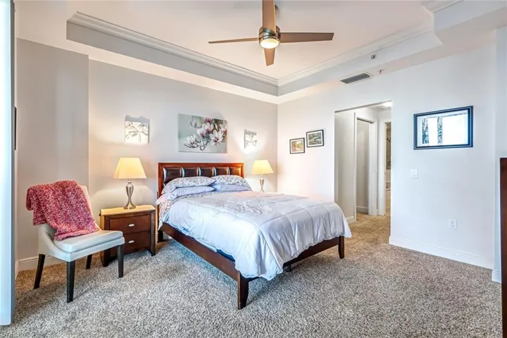 Bedroom featuring a raised ceiling, carpet, crown molding, and a ceiling fan