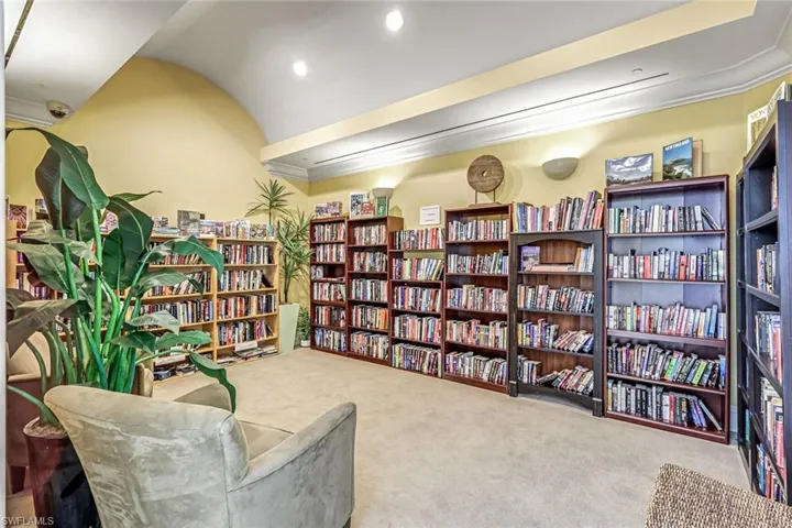 Living area with wall of books, light carpet, and recessed lighting