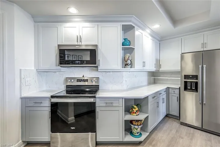 Kitchen with open shelves, appliances with stainless steel finishes, white cabinets, decorative backsplash, and recessed lighting