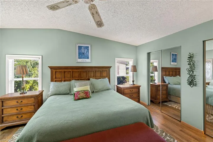 Bedroom with multiple windows, a closet, hardwood / wood-style floors, and lofted ceiling