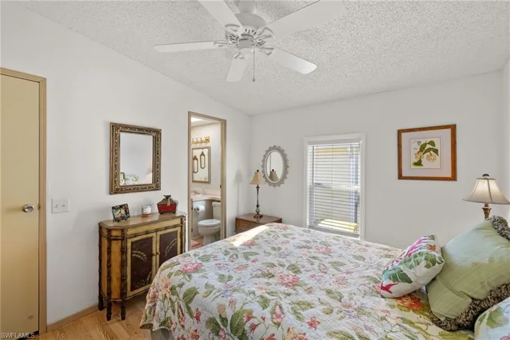 Bedroom featuring ensuite bathroom, ceiling fan, light hardwood / wood-style floors, and a textured ceiling