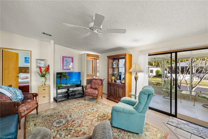 Living room featuring ceiling fan, light hardwood / wood-style floors, and a textured ceiling