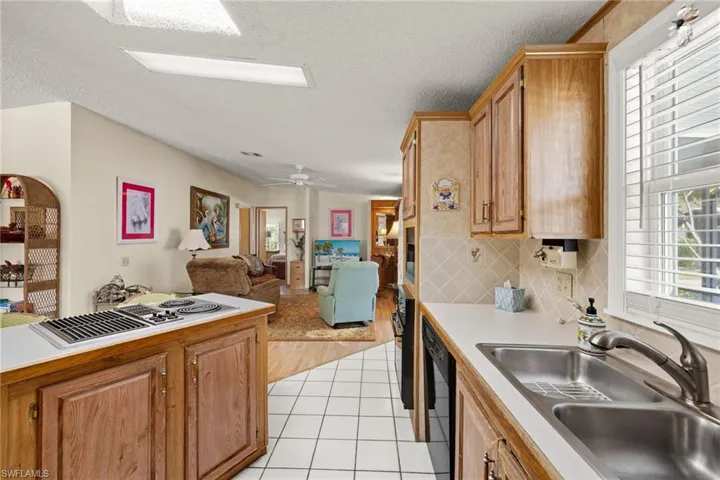 Kitchen featuring light wood-type flooring, a textured ceiling, white gas cooktop, sink, and dishwasher
