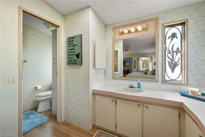 Bathroom featuring vanity, a textured ceiling, ceiling fan, hardwood / wood-style flooring, and toilet