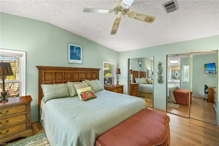 Bedroom featuring multiple windows, light hardwood / wood-style flooring, vaulted ceiling, and ceiling fan