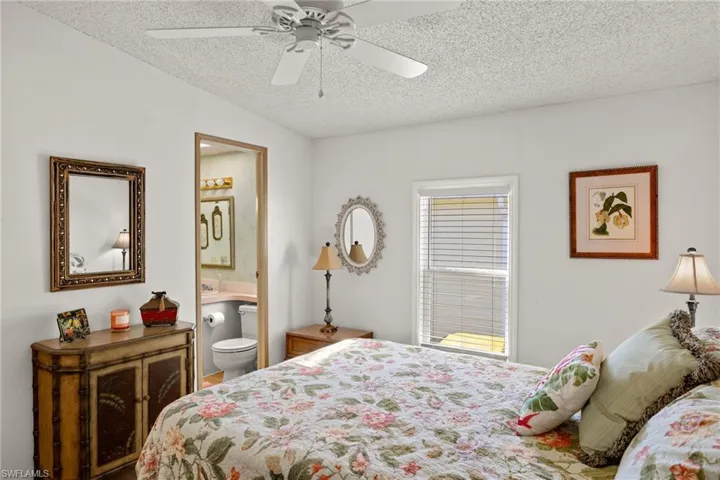 Bedroom with a textured ceiling, ceiling fan, and ensuite bathroom
